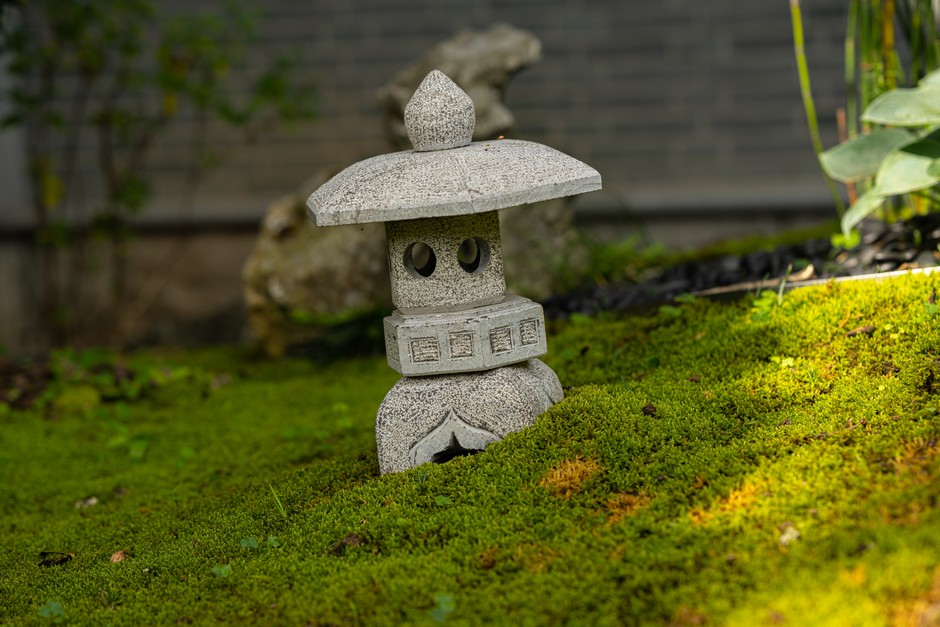 A tranquil garden scene featuring a stone lantern on lush green moss, perfect for zen ambiance.